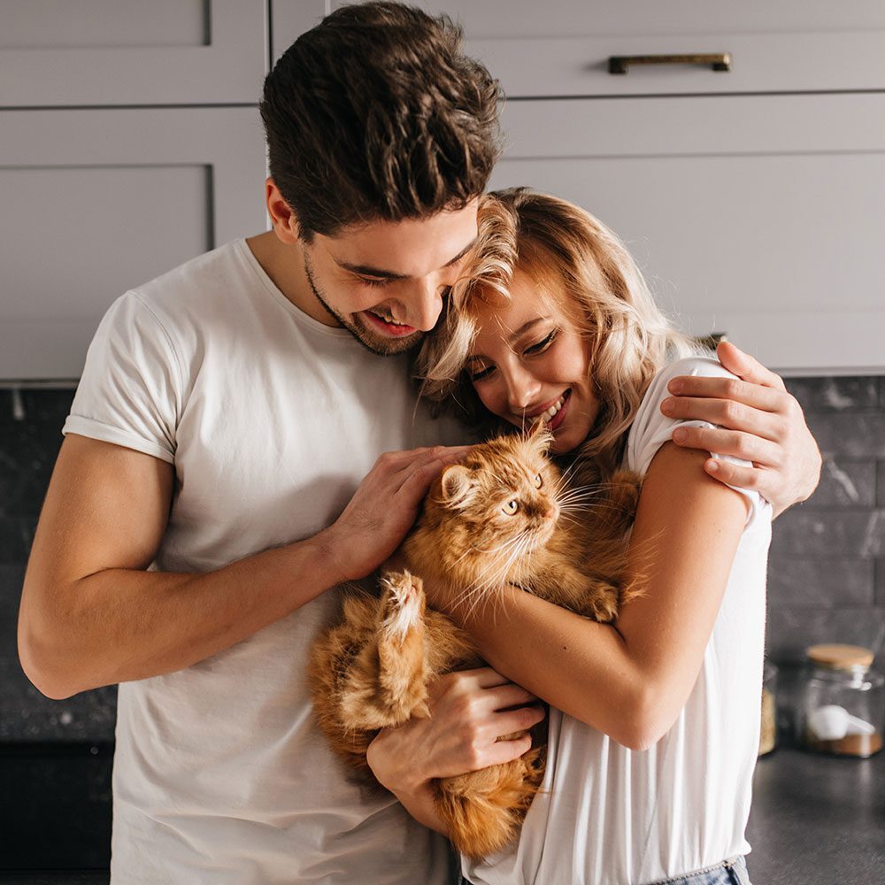 Happy Couple Holding Their Orange Cat Happy Couple Holding Their Orange Cat